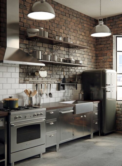 industrial-style kitchen with stainless steel cabinets, dark wood countertops, and pendant lighting. The room has a few appliances, including a stove, a refrigerator, and a sink. There are also some utensils and pots on the countertops. The walls are exposed brick, and there is a window near the refrigerator. The floor is made of concrete. Less
