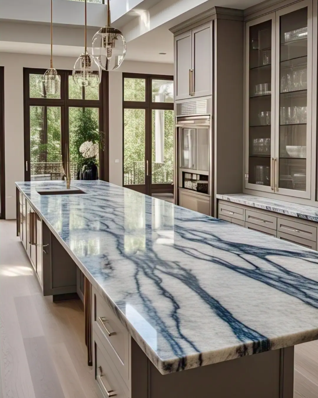 Mitered-edge granite island with dramatic blue-pearl veining, contrasting with white oak floors.