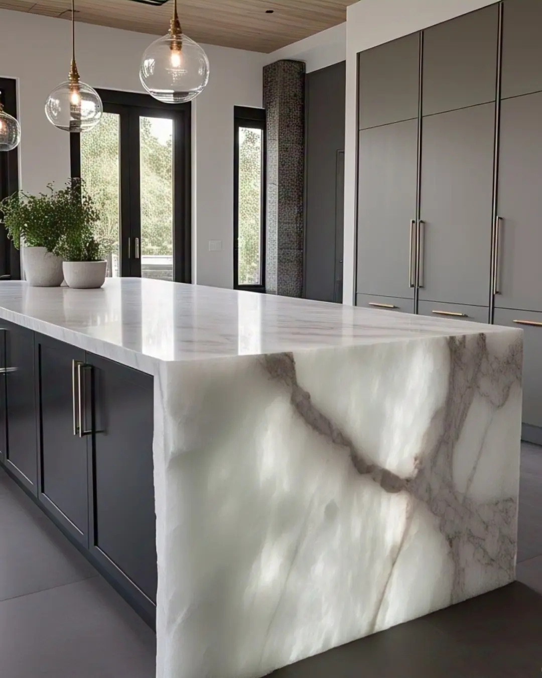 Waterfall Edge Countertop: What Is It and Why Is It So Cool? 6 White quartz waterfall island with gray veining, glowing under pendant lights. The edge flows smoothly to the floor.
